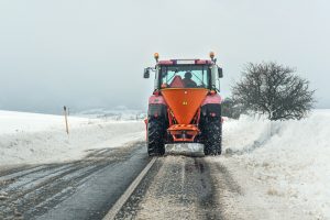 compact tractor spreading salt on icy & snowy roads UK